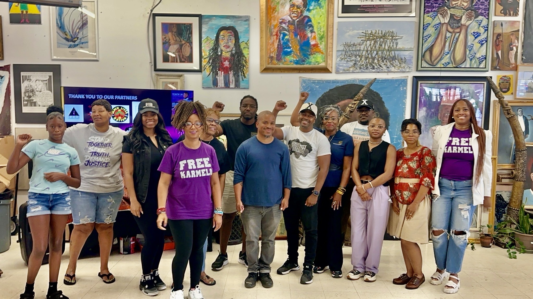Organizers and supporters at the first Karmelo Teach-In — FREE KARMELO shirts, fists raised — Pan African Connection Bookstore, Dallas, August 2026